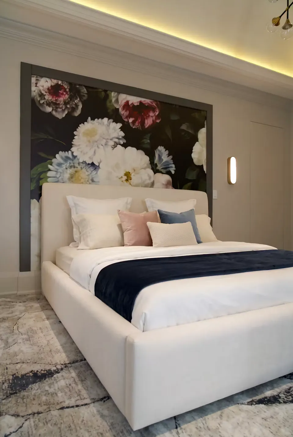 Angled detail of the ivory headboard, pale pillows and navy bedding.