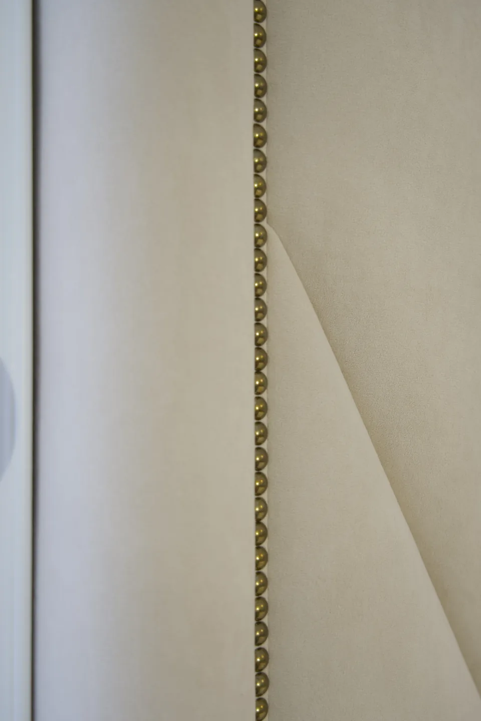 Detail of the decorative gold-toned edge beside the ivory upholstery
