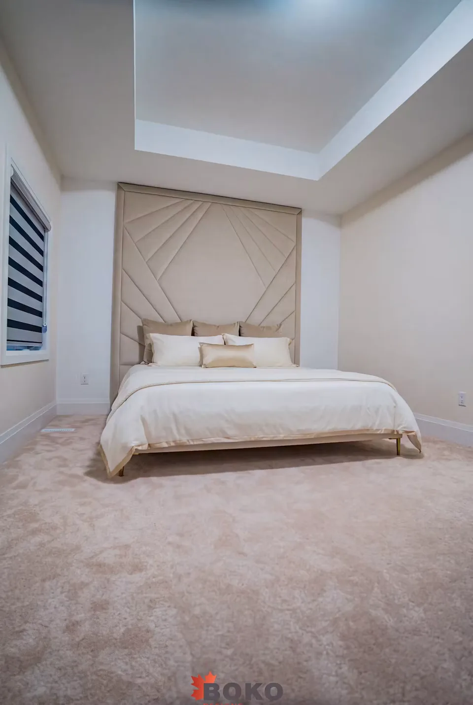 Wide room view of the ivory bed beneath a framed ray headboard