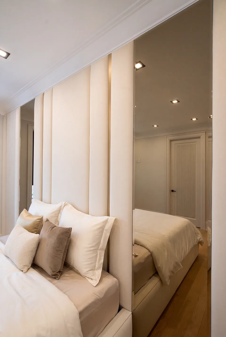 Close side view of ivory headboard panels reflected in a tall mirror.