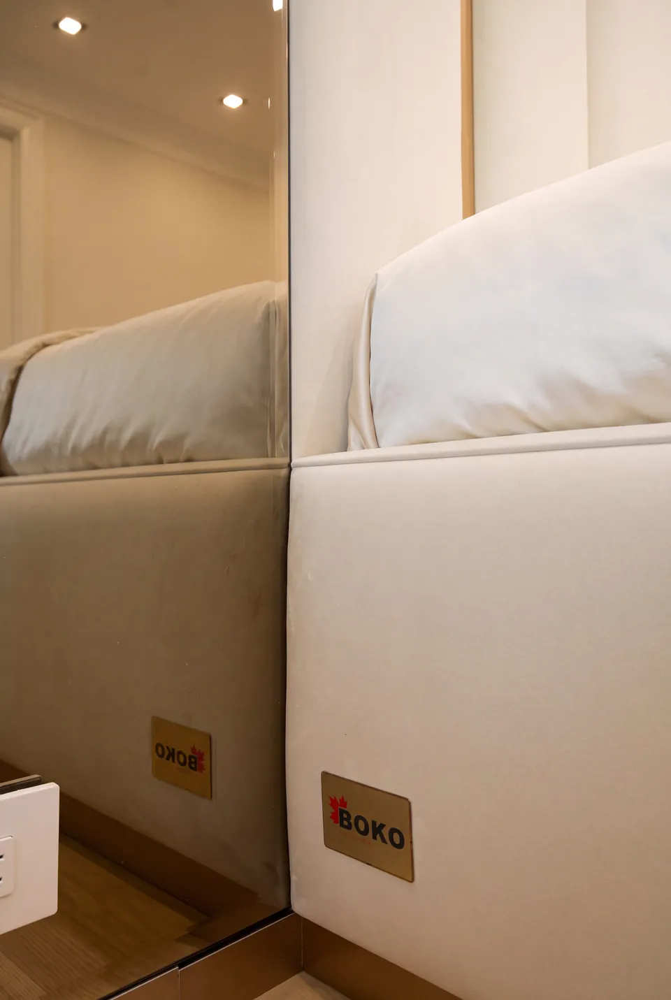 Close view of the ivory upholstered side rail and its reflection in a narrow mirror.