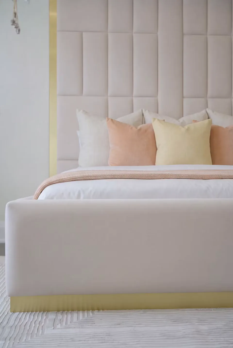 Front detail of the ivory upholstered bed base and its narrow gold-toned trim