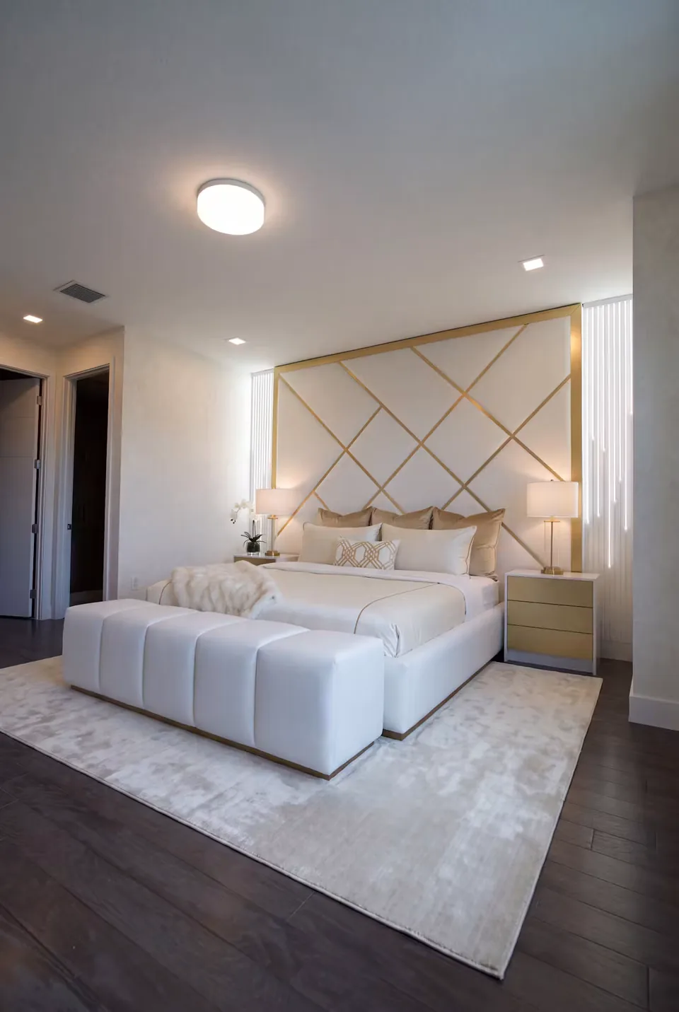 Full angled view of the ivory bed beneath the gold-lined upholstered wall