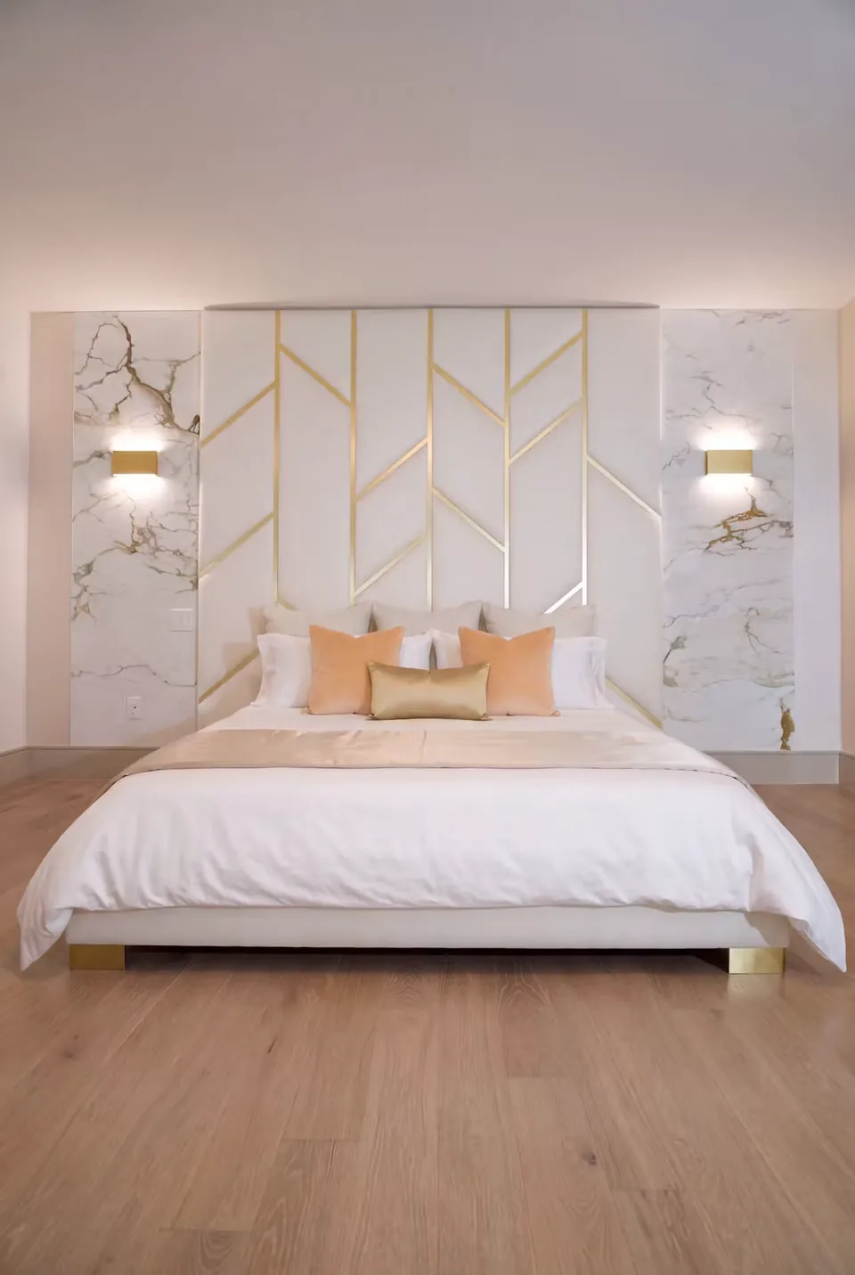 Ivory upholstered bed beneath gold-toned branching lines and pale patterned wall panels