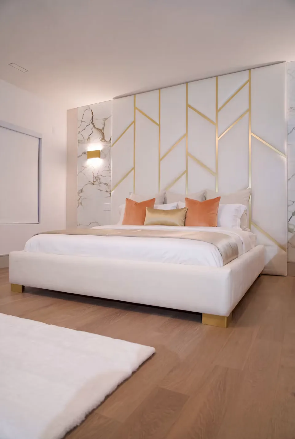Angled view of the ivory bed and tall gold-lined headboard on a wood floor