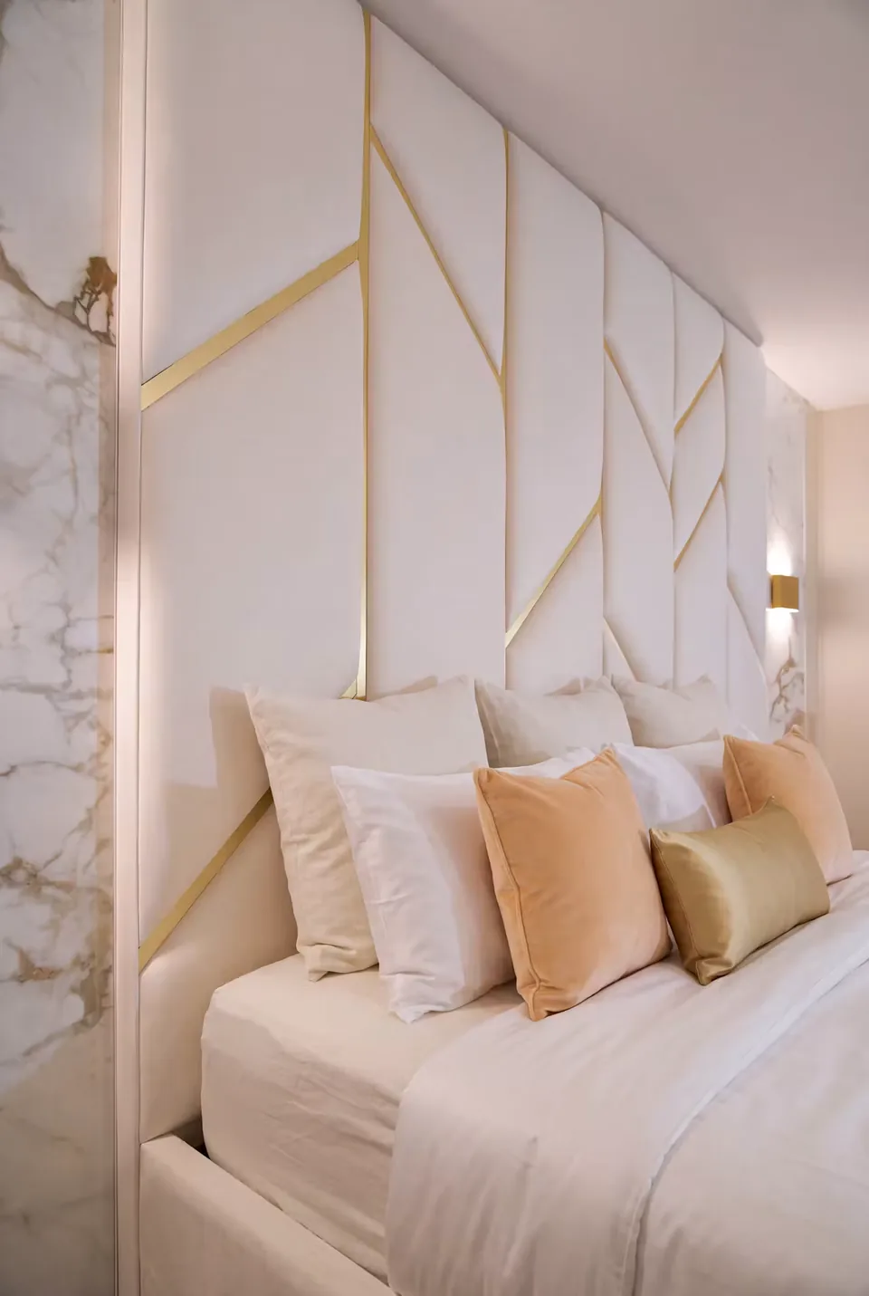 Close view of gold-toned lines across the tall ivory padded headboard