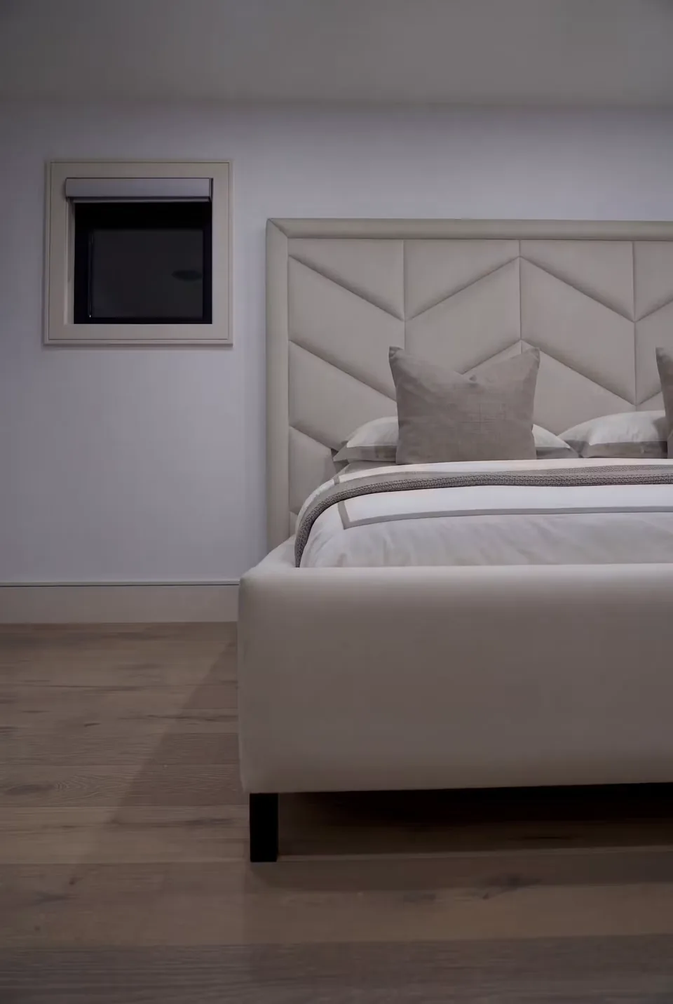 Detail of the pale footboard beneath the low geometric headboard