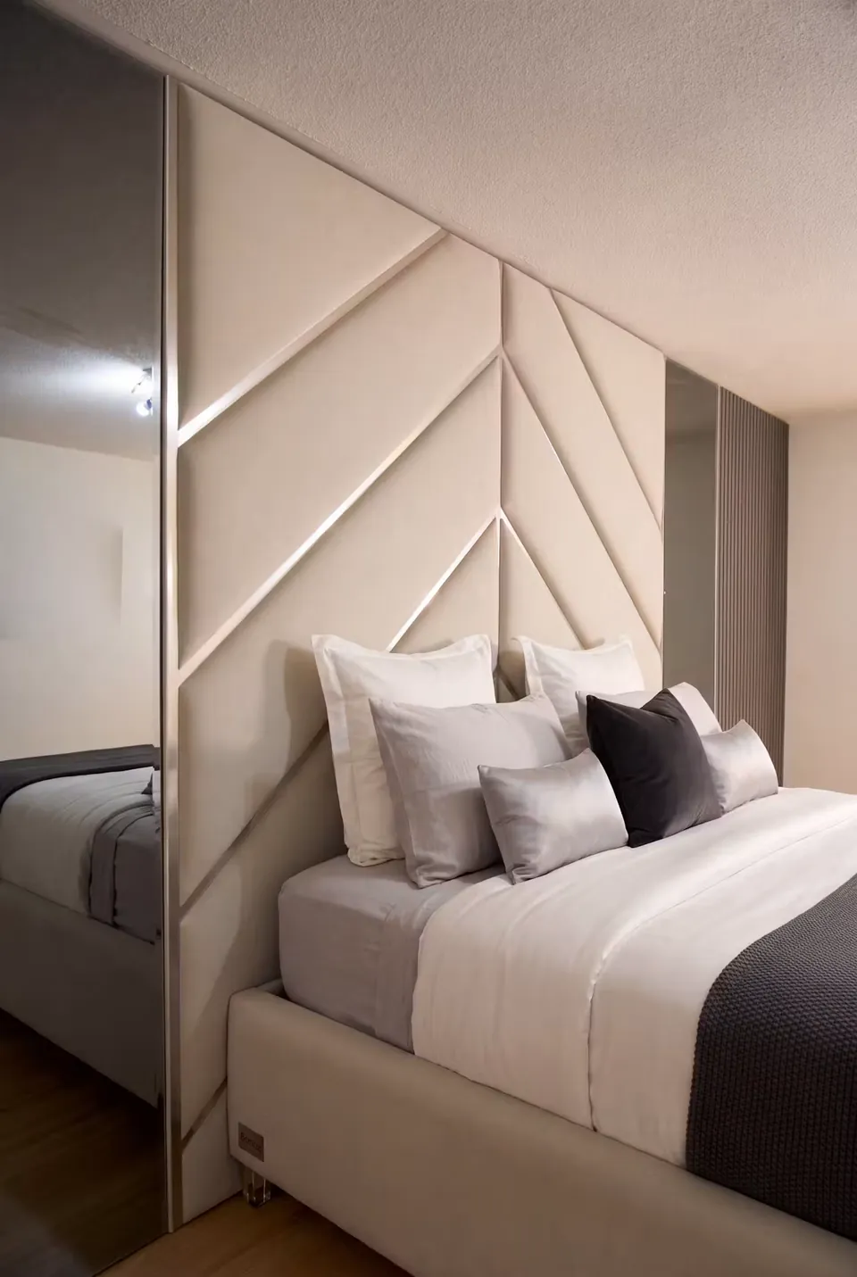 Side view of the ivory upholstered bed beside its mirrored headboard section.