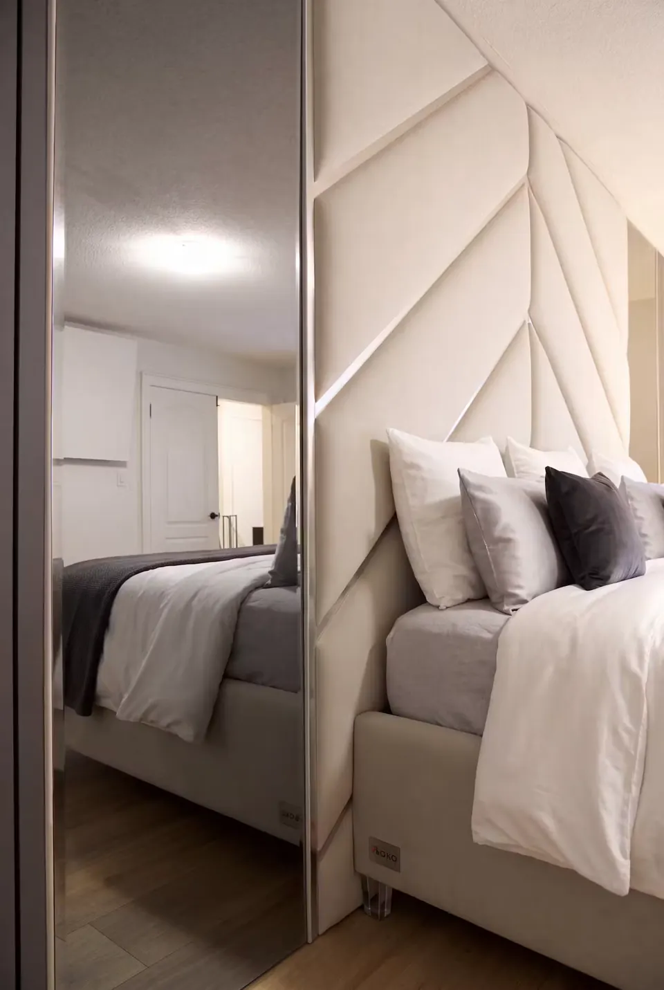 Close view of an ivory chevron panel and the bed reflected in a tall mirror.
