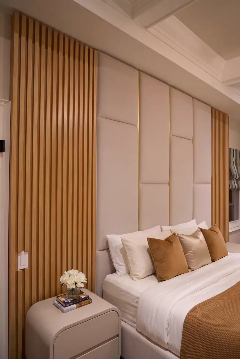 Close side view of the ivory grid headboard beside warm vertical slats and a bedside table.