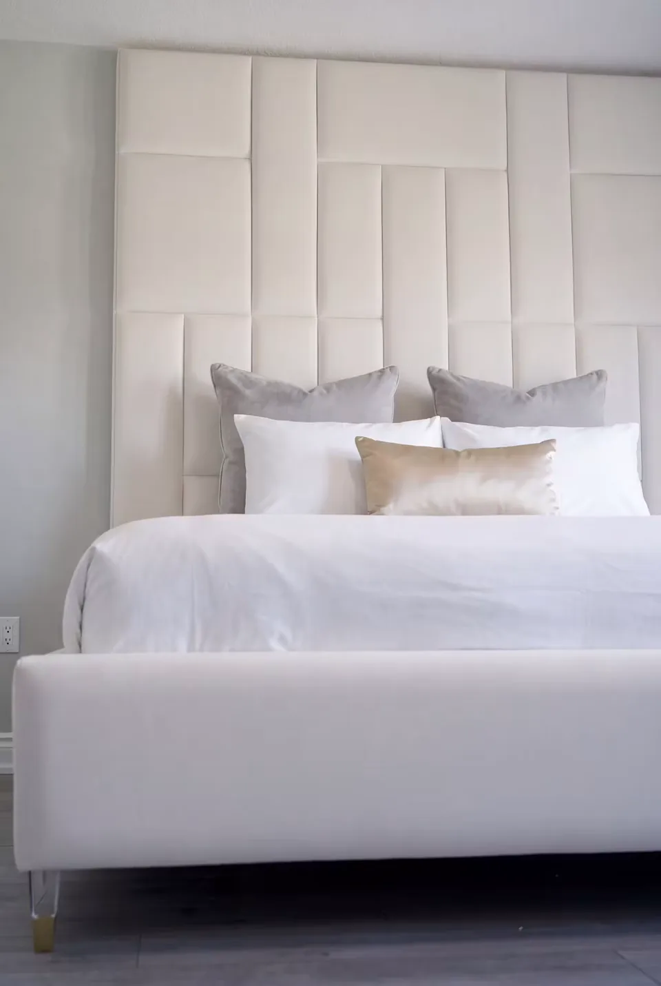 Ivory upholstered bed beneath a tall offset rectangular panel wall