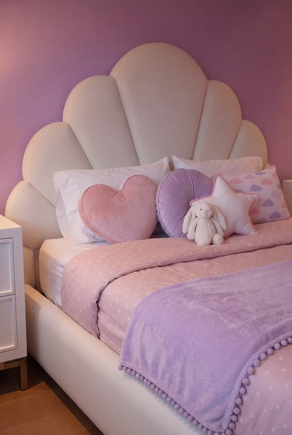 Close view of the scalloped ivory headboard and curved padded panels
