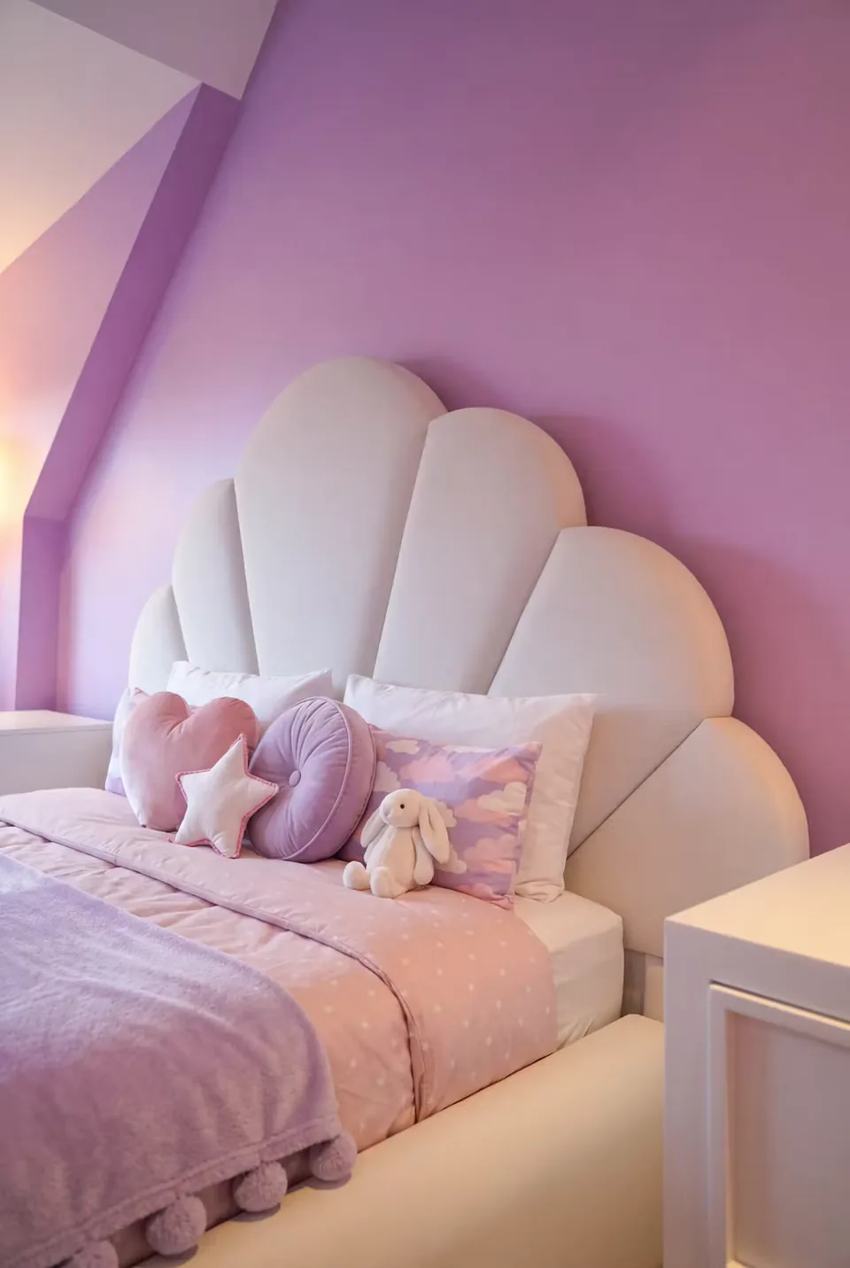 Angled view of an ivory petal bed beside a small white bedside table