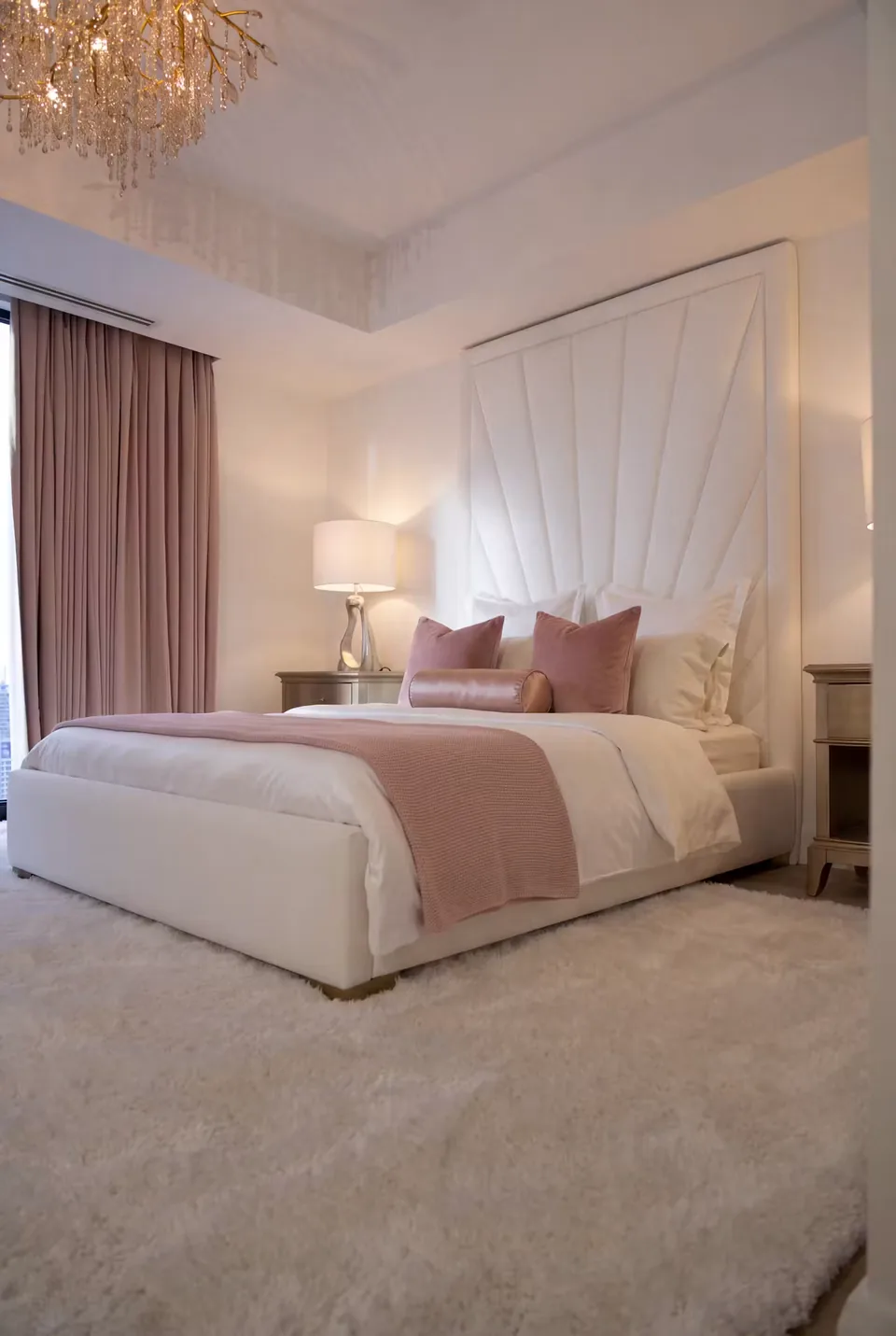 Ivory fan-shaped wall headboard above a matching upholstered bed with pink bedding