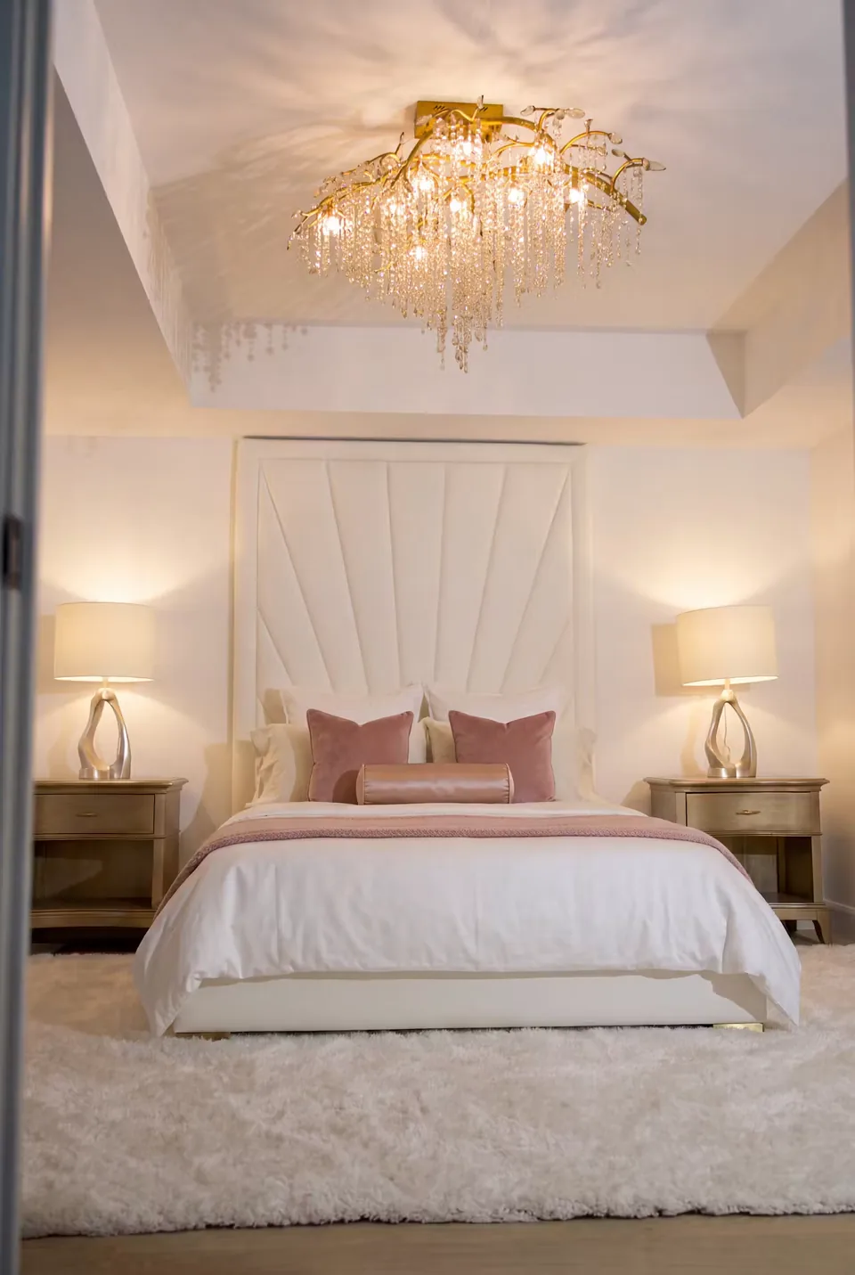 Front view of the radiating ivory headboard beneath a glass chandelier
