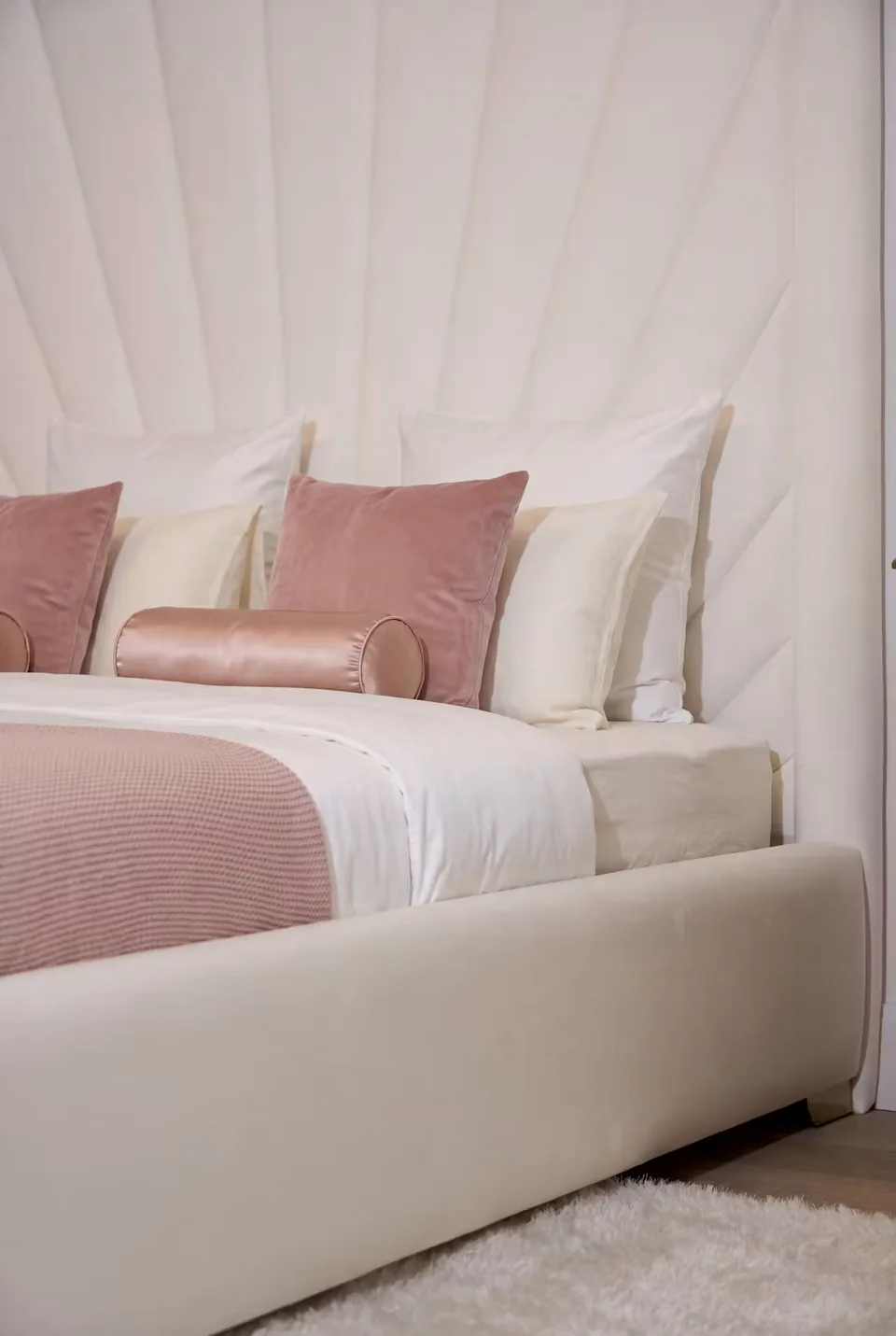 Detail of the smooth pale footboard and radiating upholstered wall behind it