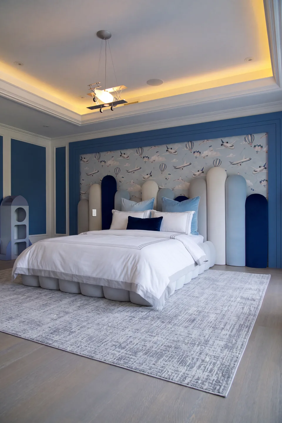 Wide room view of the rounded ivory bed against the blue bordered wall