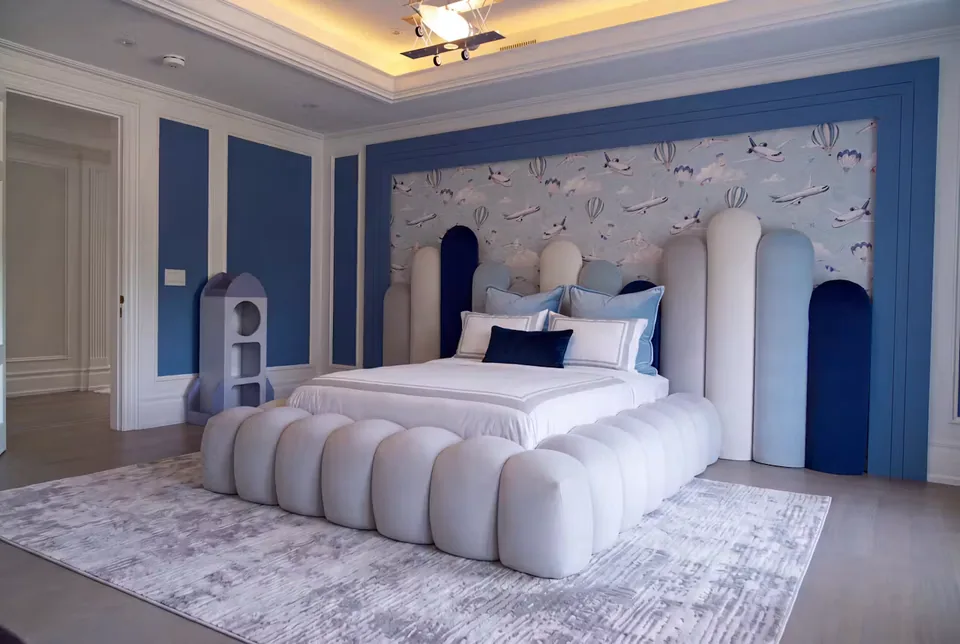 Wide landscape view of the ivory rounded bed and surrounding room