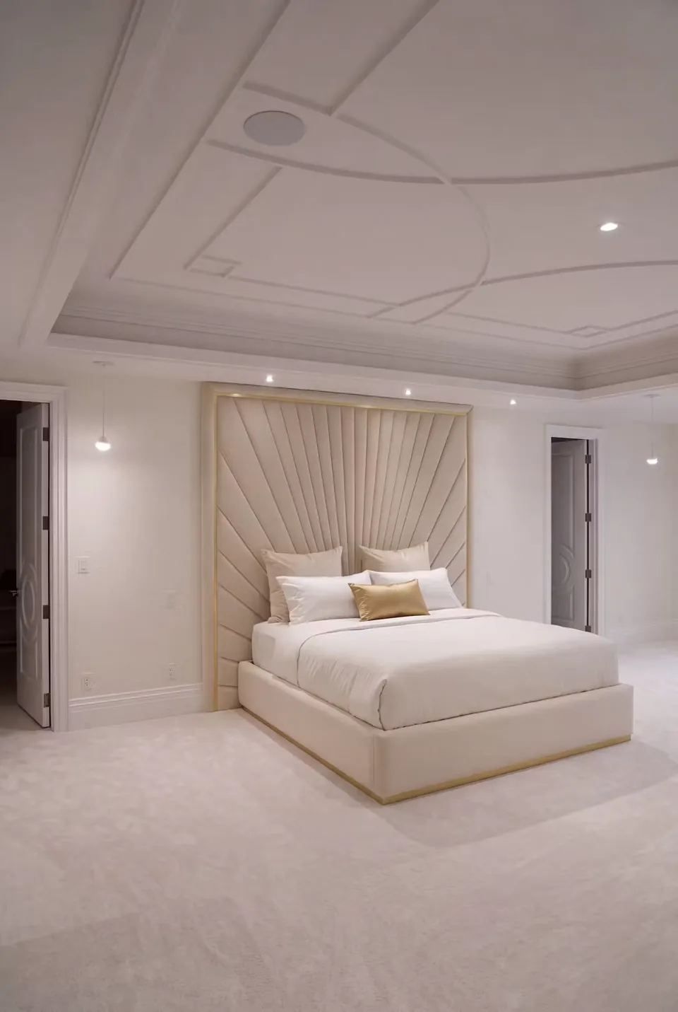 Wide bedroom view of the ivory padded wall and gold-edged bed