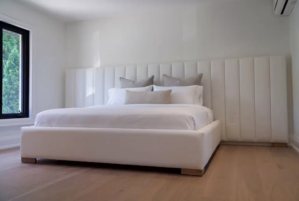 Front view of the full ivory bed and wide channelled wall beside the window
