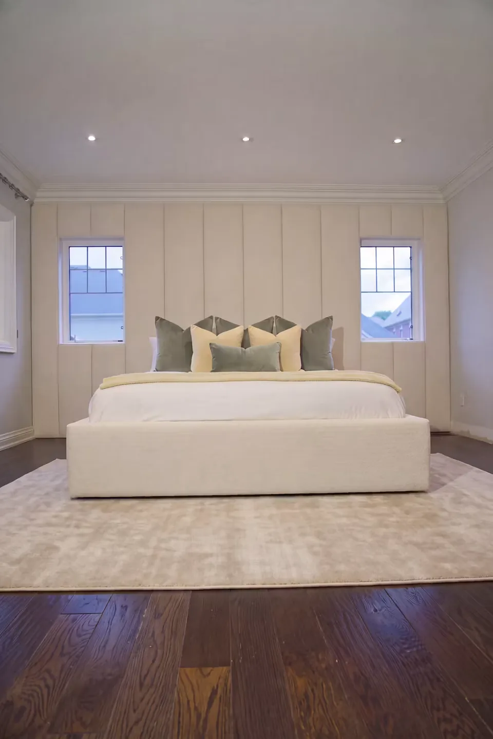 Full front room view of the ivory bed between two small windows