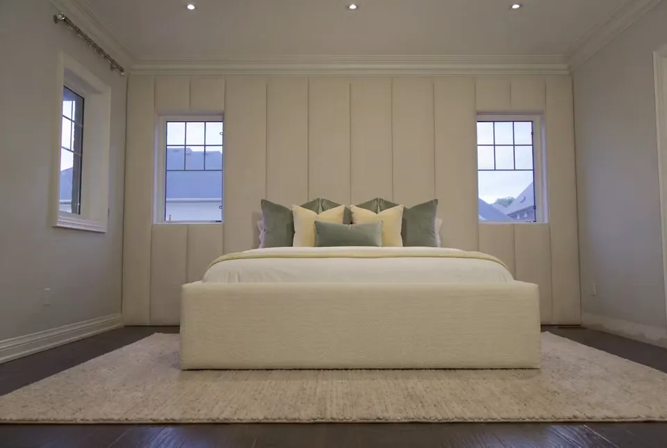 Wide front view of the ivory bed beneath the window panel wall