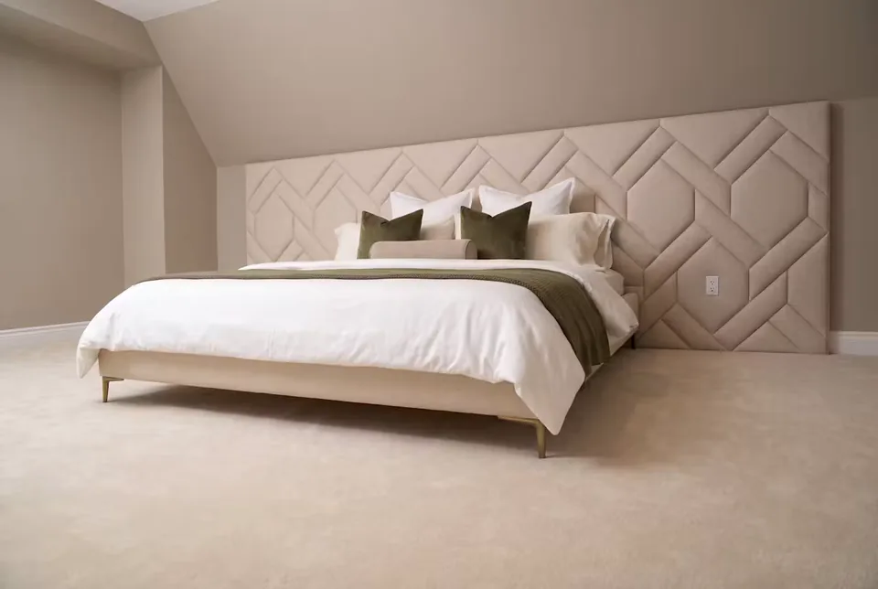 Second wide view of the ivory bed beneath the interlocking upholstered wall pattern.