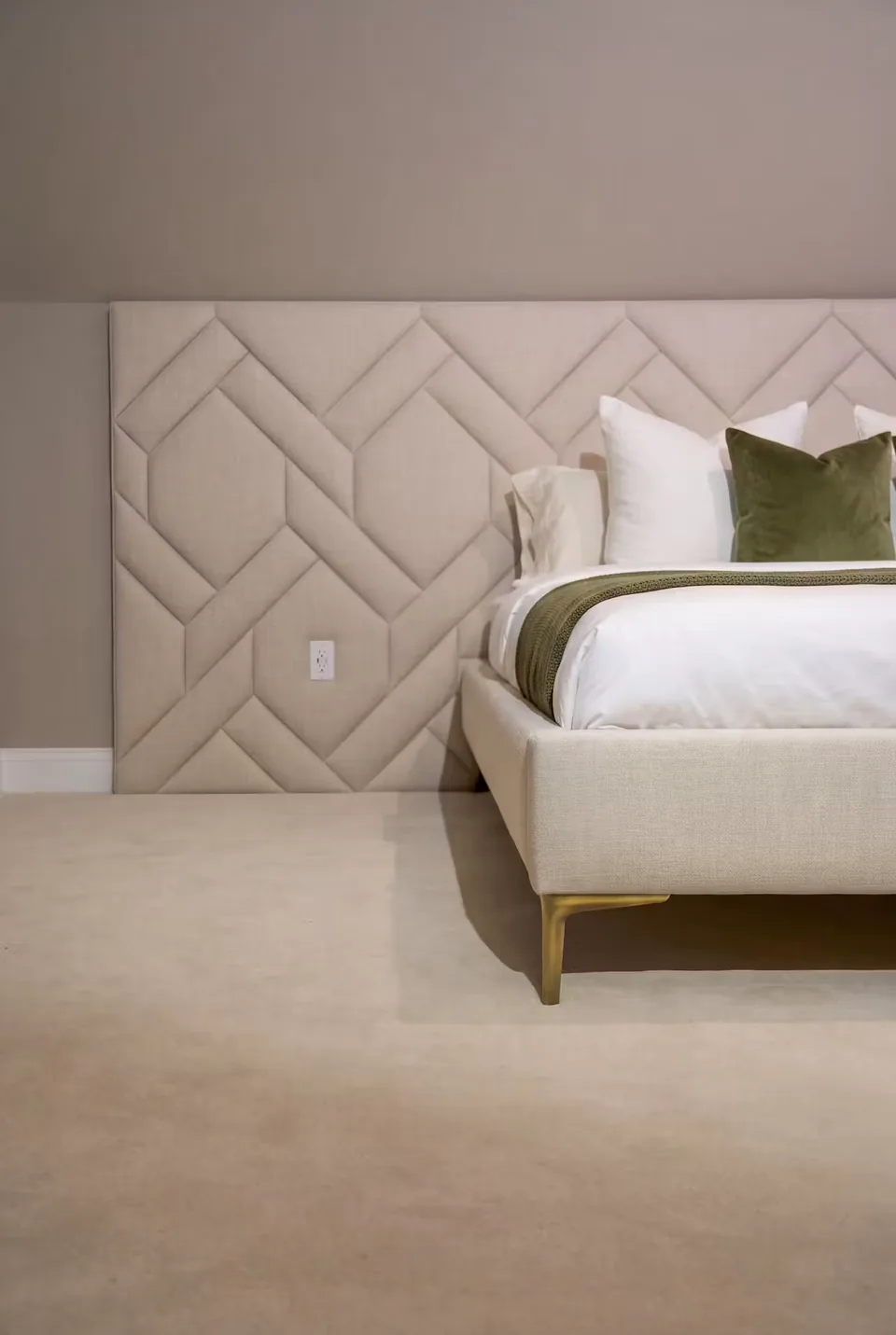 Side view of the broad ivory padded wall extending beyond the bed frame.