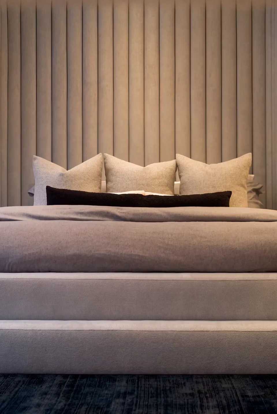 Front view of the grey bed, white cushions and two-level upholstered base