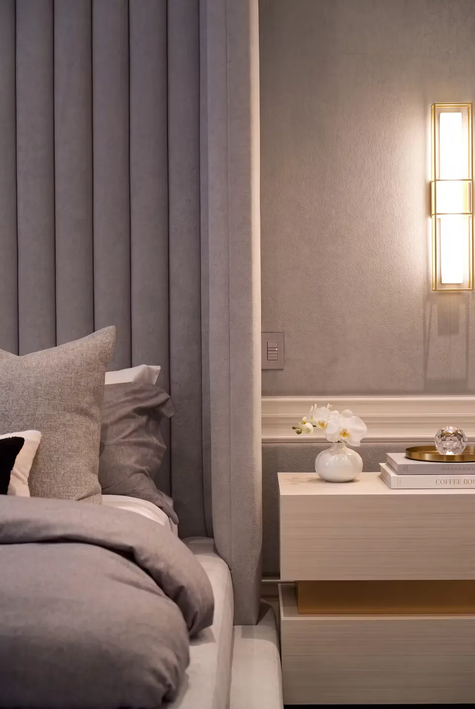 Close view of grey wall channels, cushions and a lit bedside wall lamp