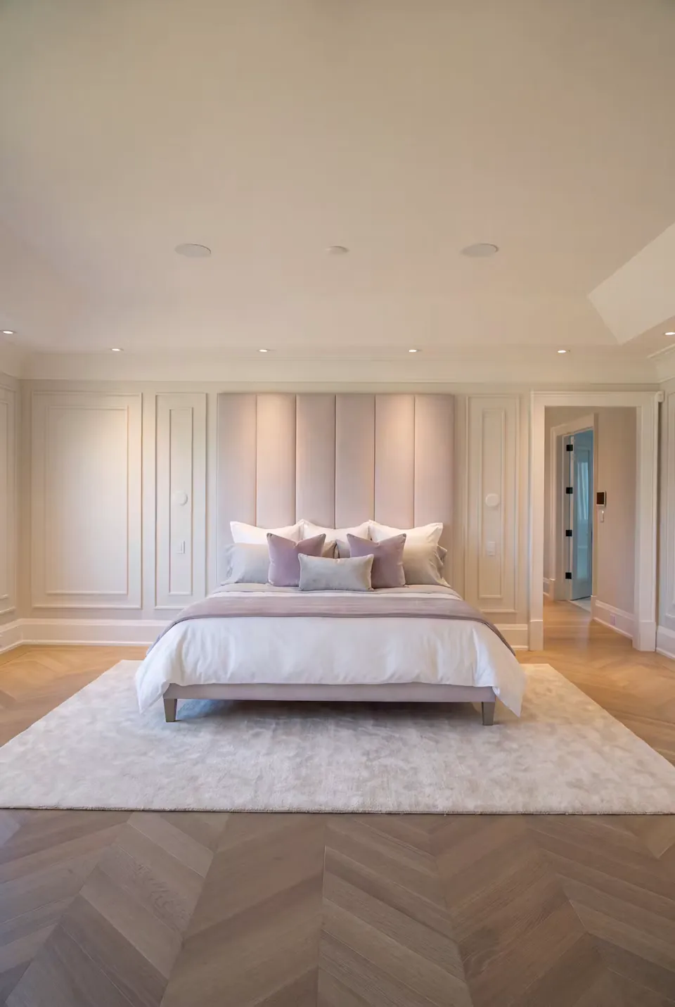 Wide front view of the lilac bed on a rug above herringbone flooring.