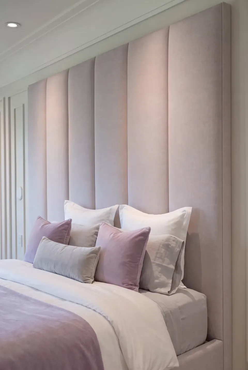 Detail of the pale lilac wall padding and purple cushions.