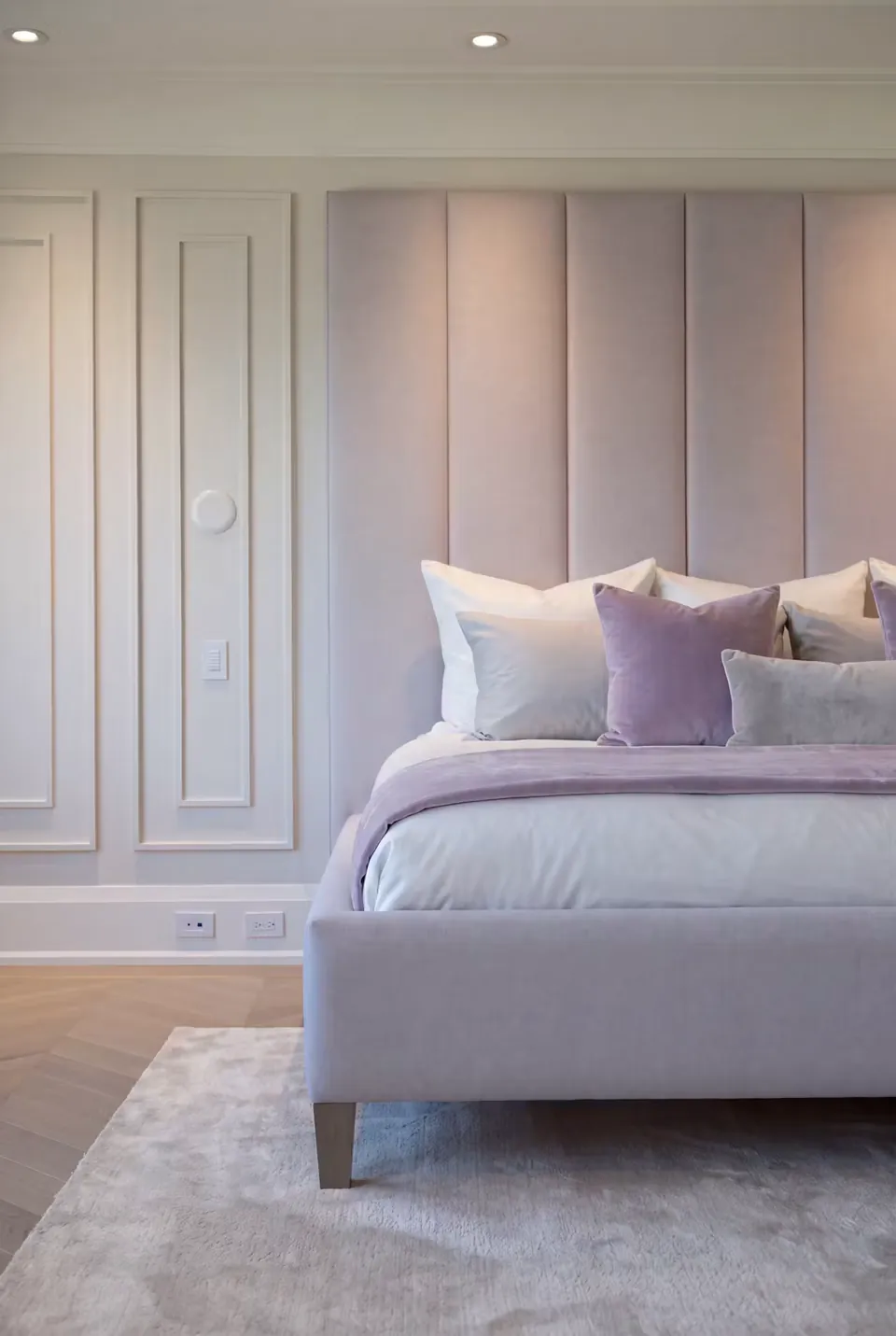 Close front view of the lilac bed frame, metallic leg and tall upholstered panels.