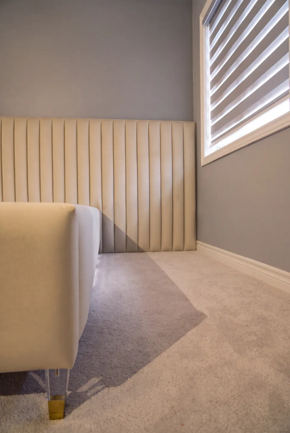 Detail of the ivory bed frame, metallic foot and low vertical wall channels.