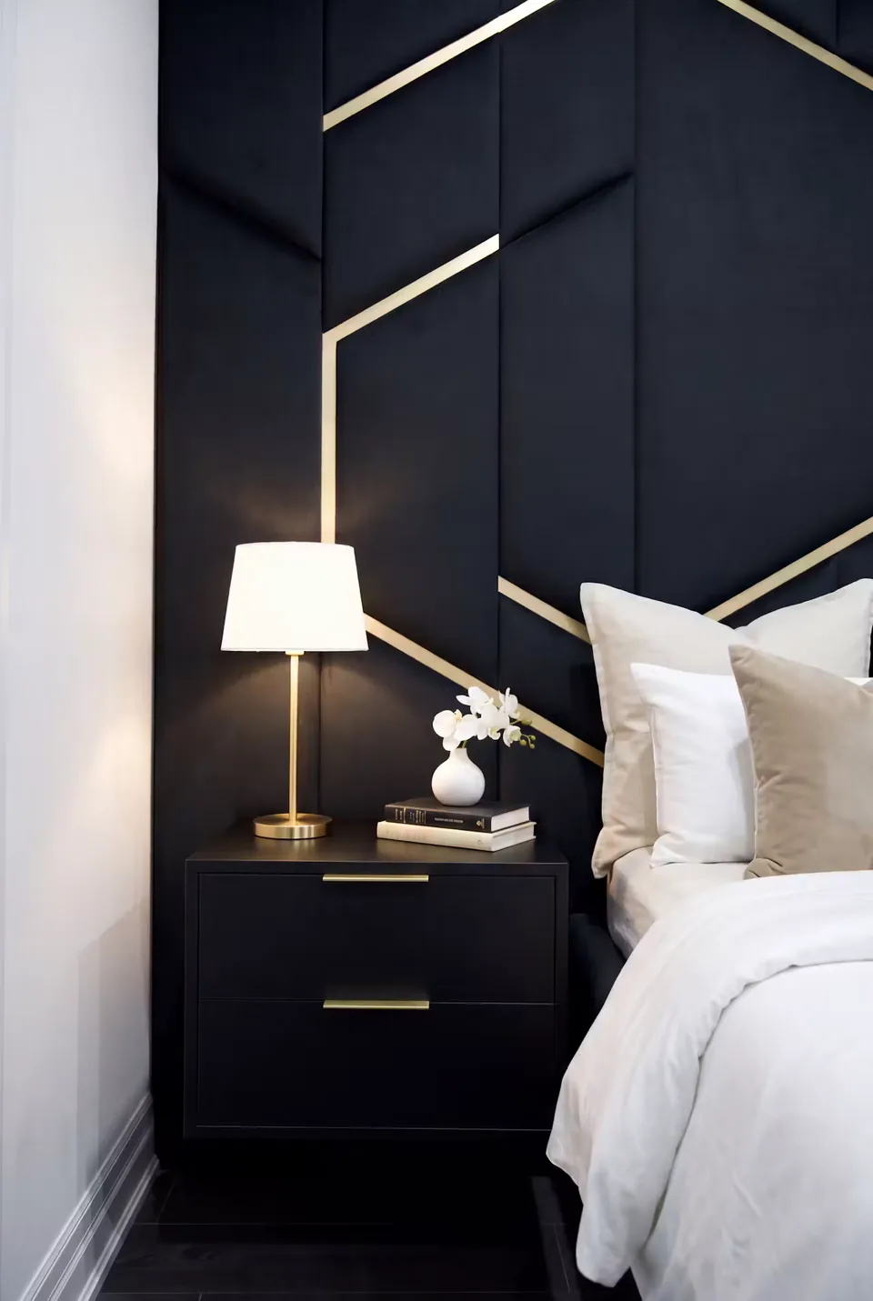 Close view of a bedside lamp beside the dark gold-lined headboard