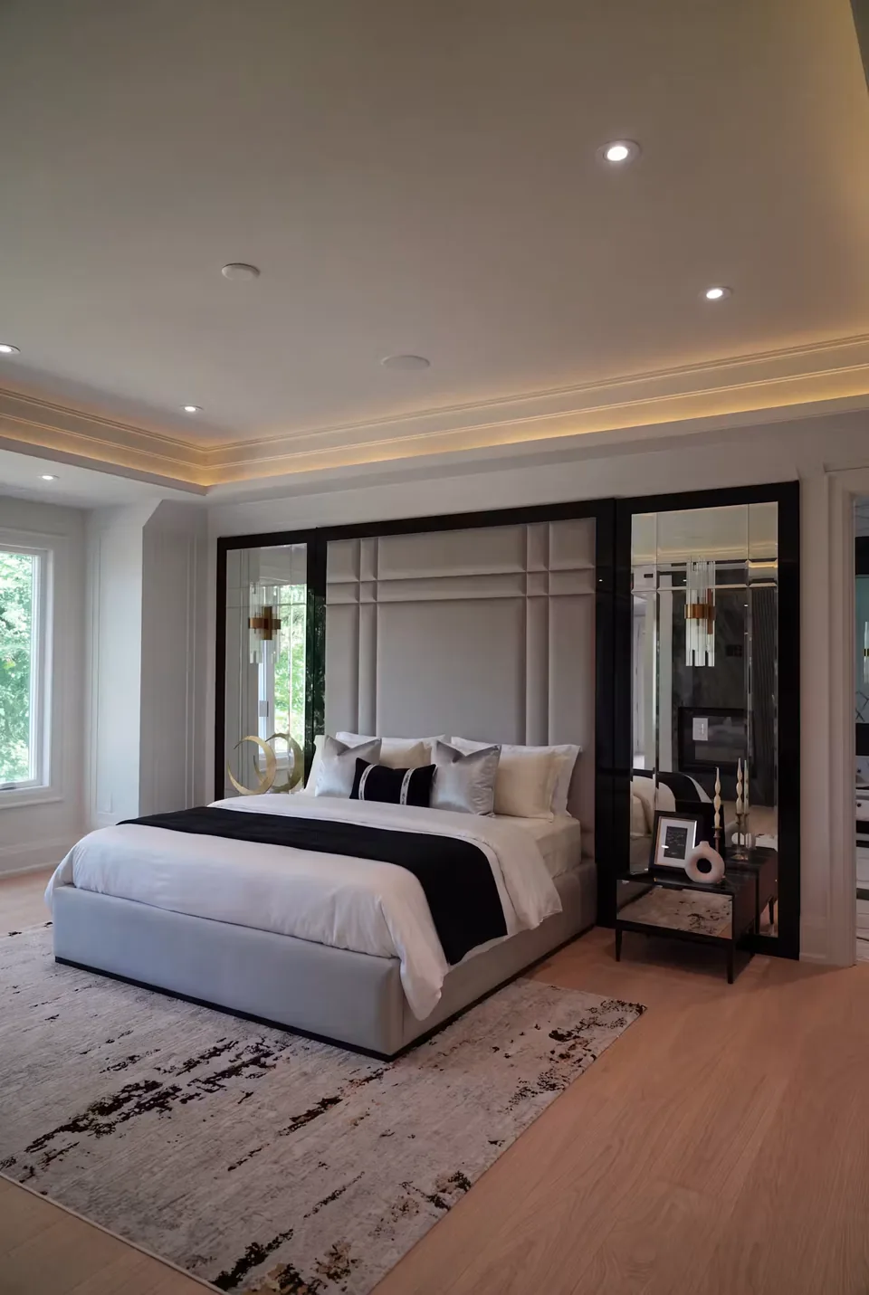 Pale upholstered bed and rectangular headboard inside a black surround with mirrored side panels
