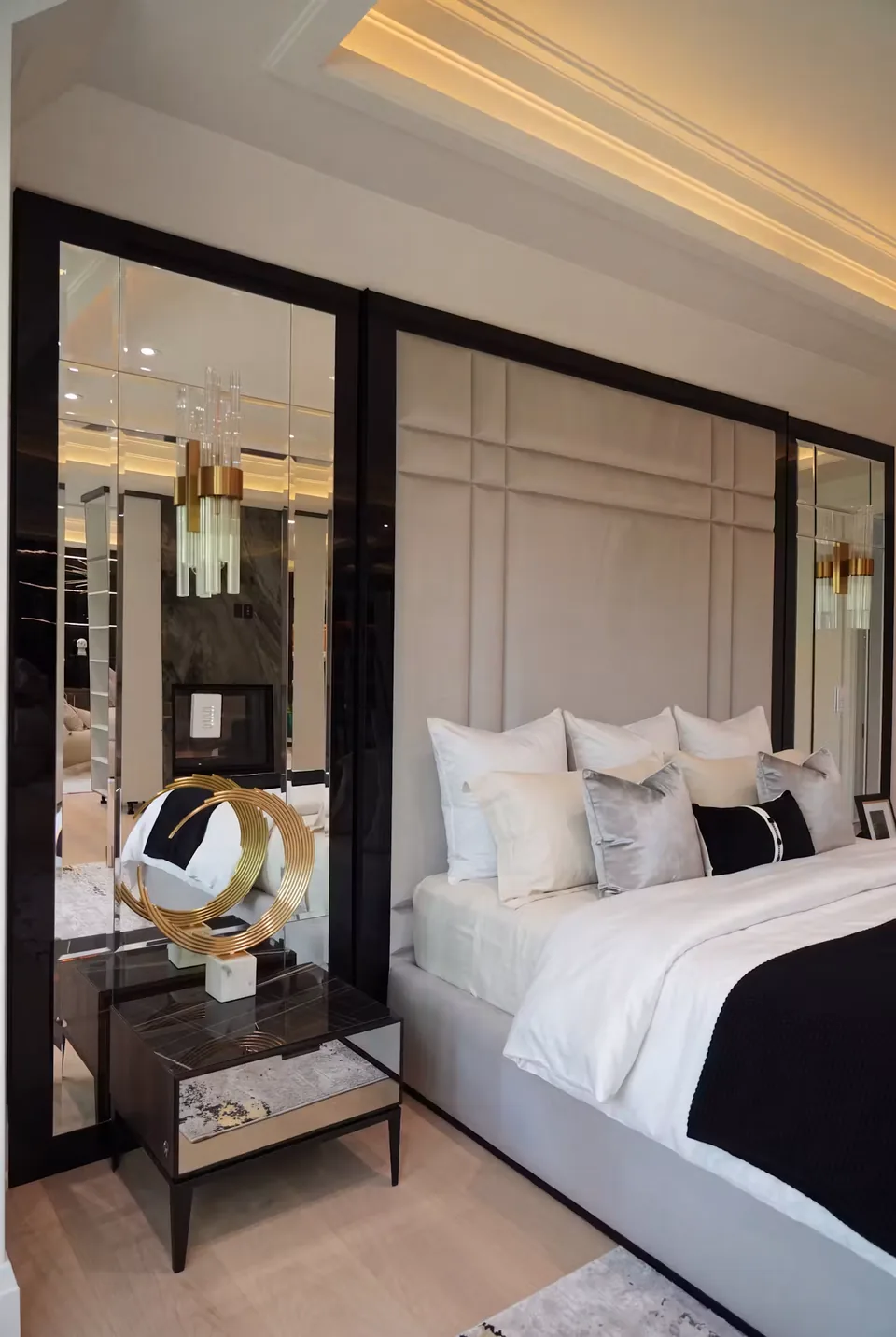 Close view of padded headboard rectangles beside a mirror and a bedside pendant