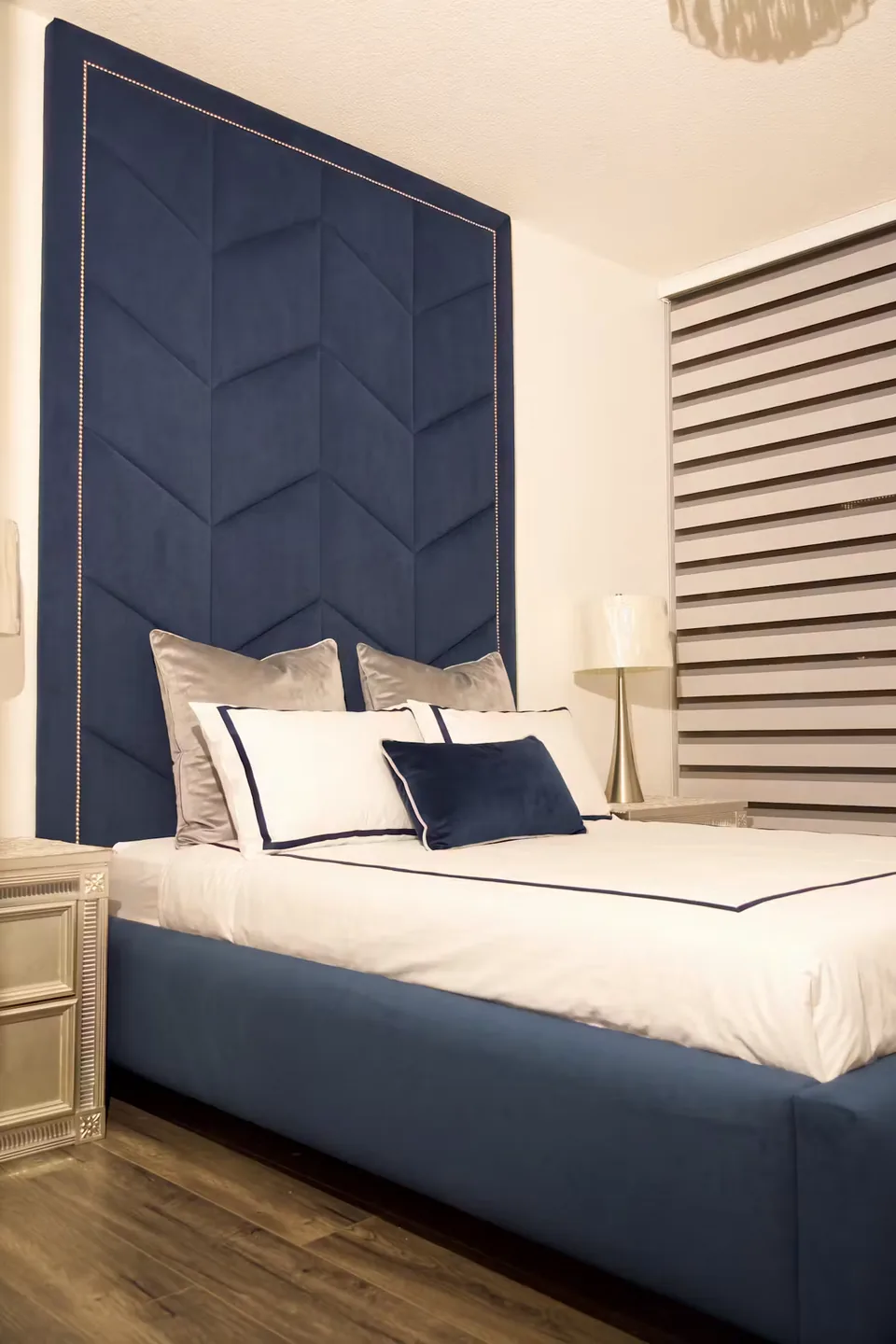 Angled view of the navy bed beneath the tall chevron headboard