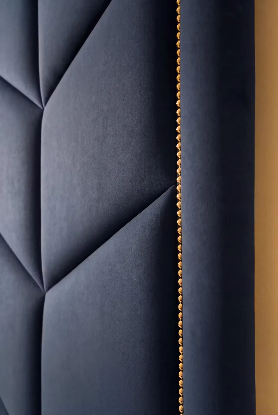 Close detail of the navy upholstery and gold-toned studded edging