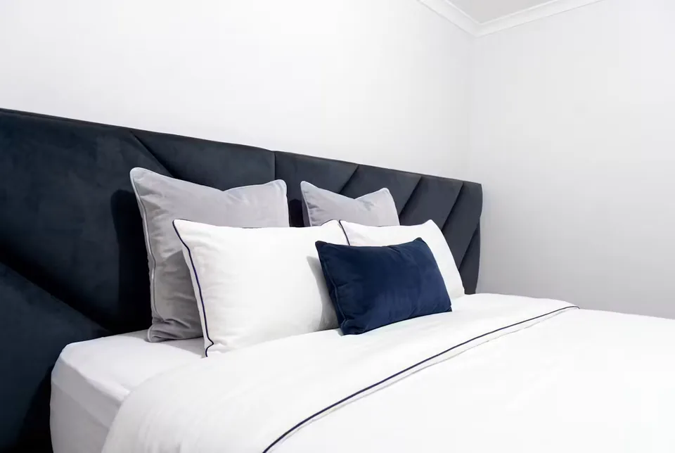 Wide close view of the navy diagonal headboard and white pillows