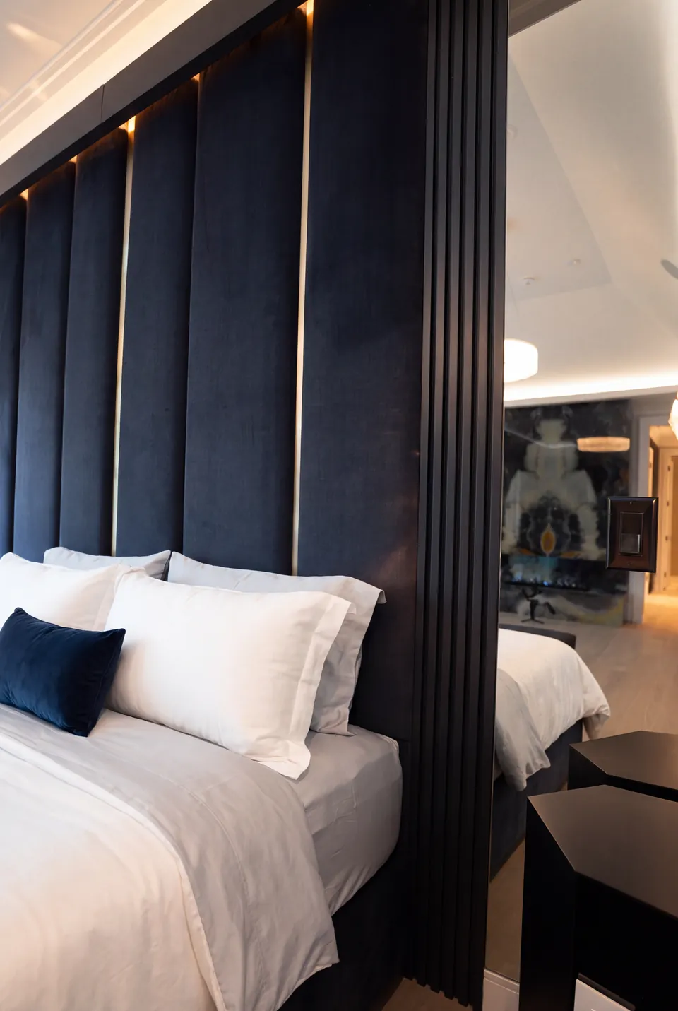 Close side view of navy panels, a gold division and white pillows beside a mirror.