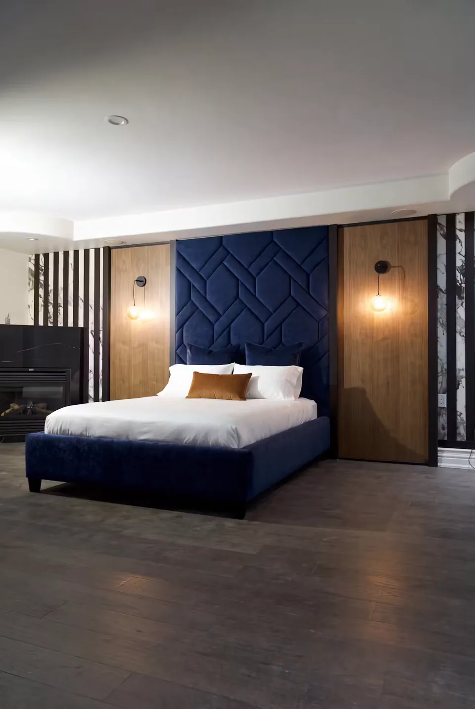 Wide view of the navy bed between warm wood and dark slatted panels