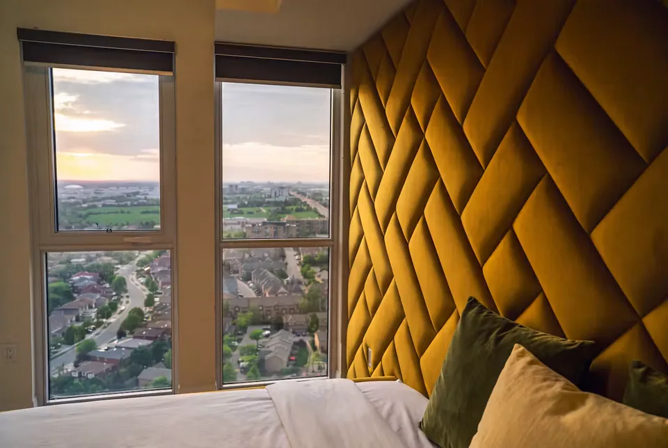 Side view of the ochre padded wall beside the corner windows