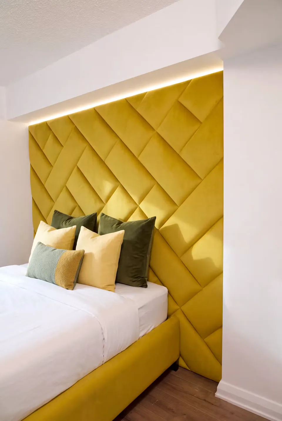 Close view of the golden yellow padded wall beside the pillows