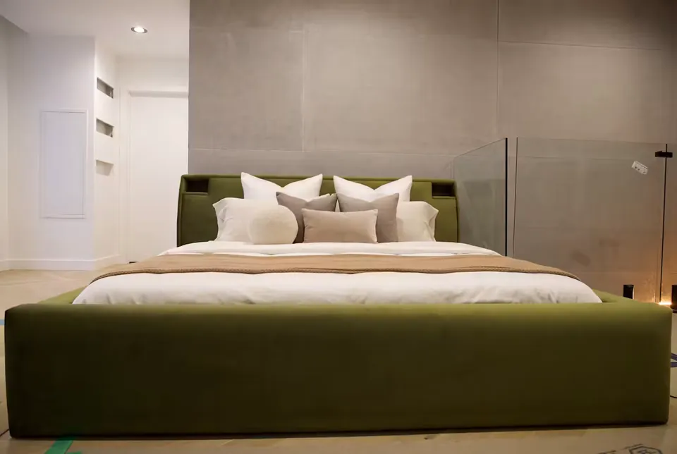 Full front view of an olive upholstered bed with recessed headboard corners and a broad footboard.
