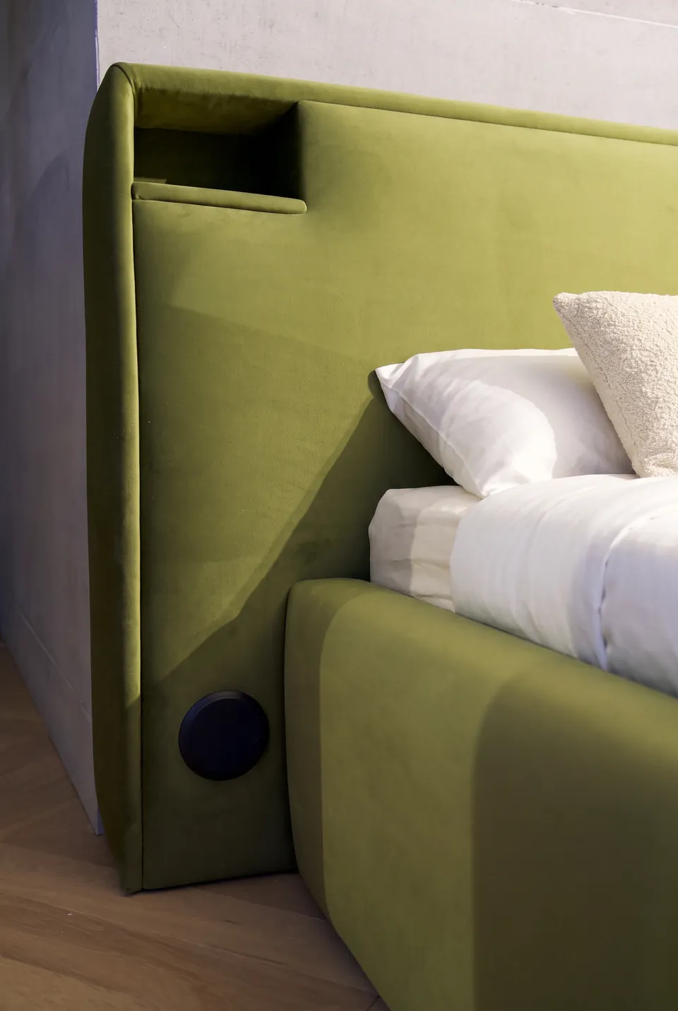 Detail of an open corner recess in the olive upholstered headboard.