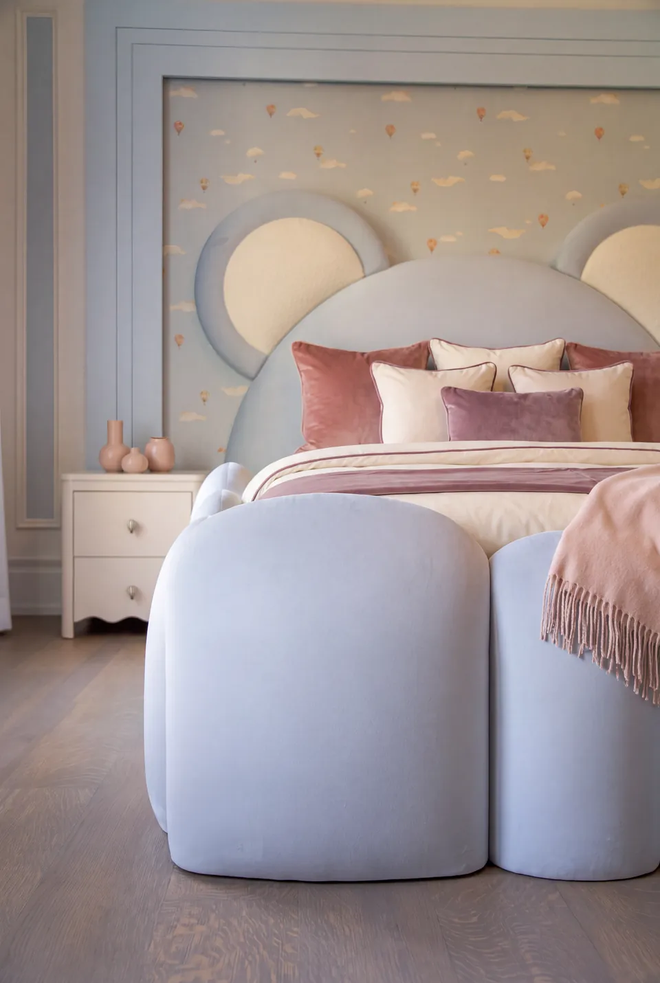 Close view of rounded powder-blue footboard sections and pink bedding.