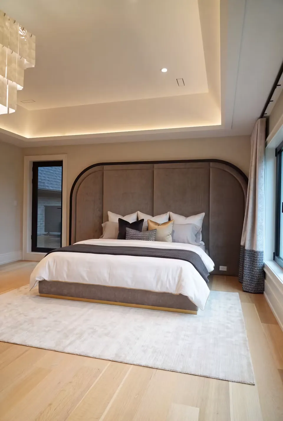 Wide view of the grey bed, curved dark border and pale timber floor.