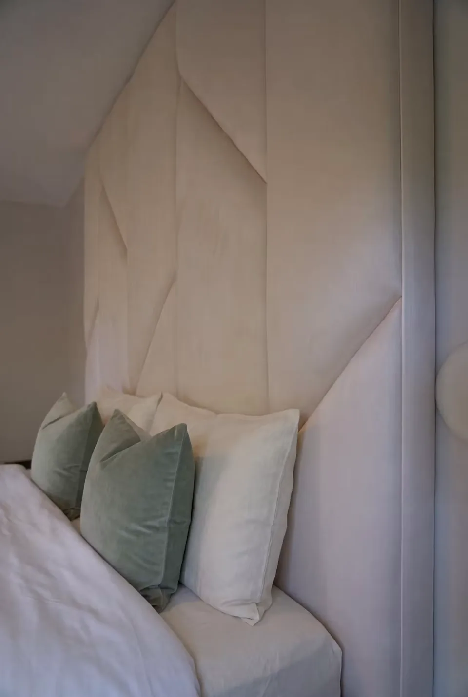 Close view of angled headboard seams above green and cream cushions