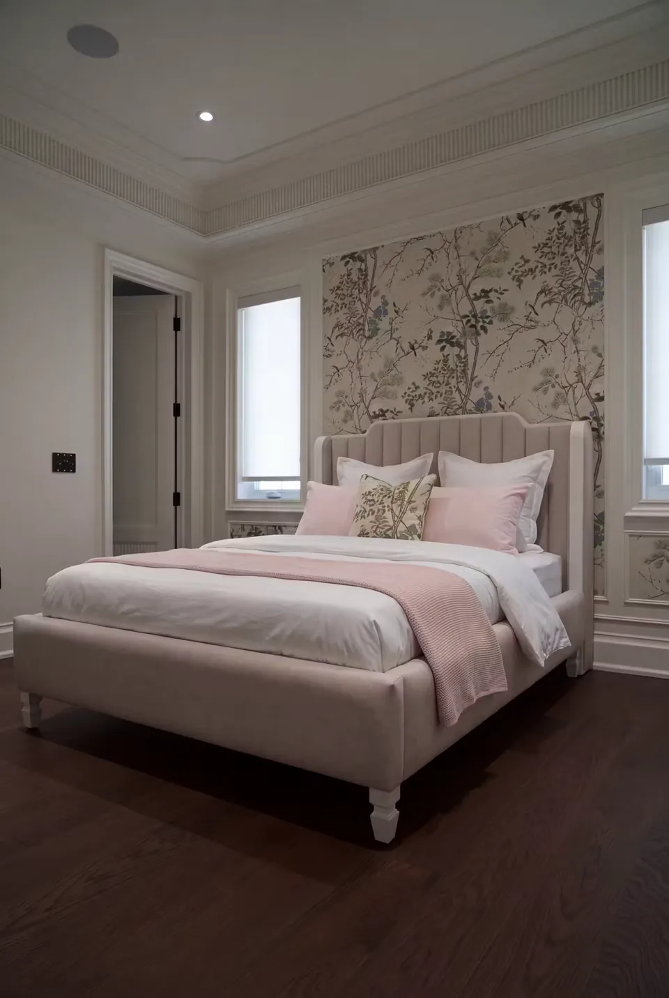 Sand upholstered bed with a bordered channel headboard and blush bedding